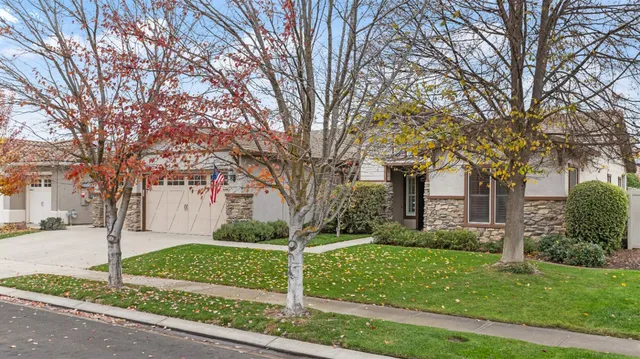 a front view of a house with a yard and large trees