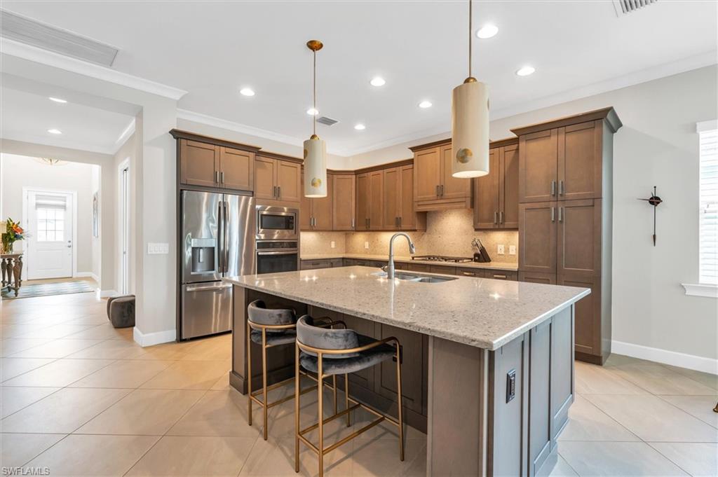 5769 Anegada Drive Naples, FL 34113 - Photo 13 of 45 a kitchen with kitchen island a sink stove and refrigerator