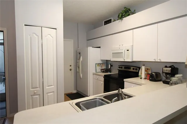 a kitchen with a refrigerator and white cabinets