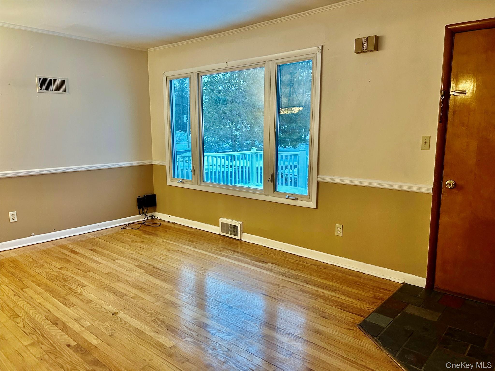 Living room with large picture window and hardwood flooring and crown molding