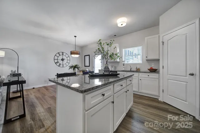 a kitchen with granite countertop a sink cabinets and wooden floor