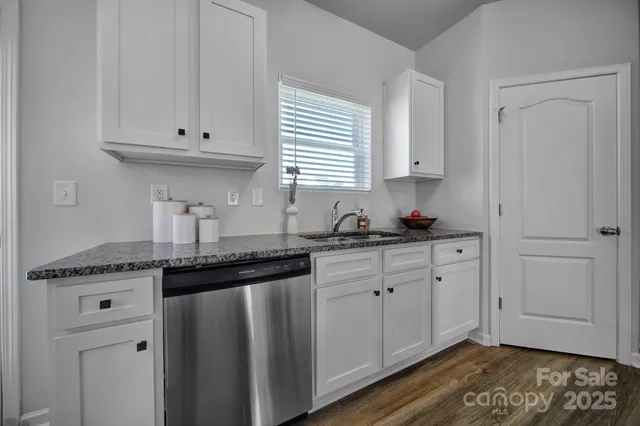 a kitchen with granite countertop white cabinets and sink