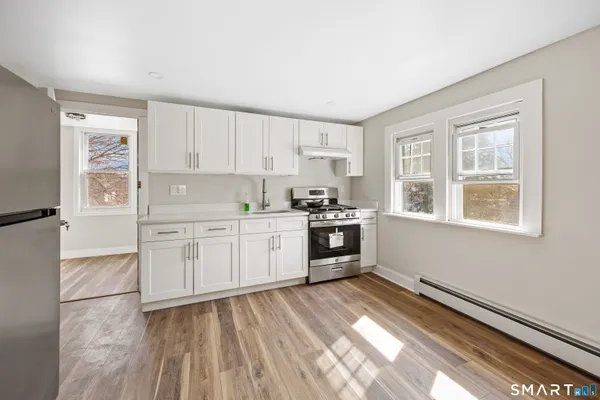a view of a kitchen with white cabinets and refrigerator
