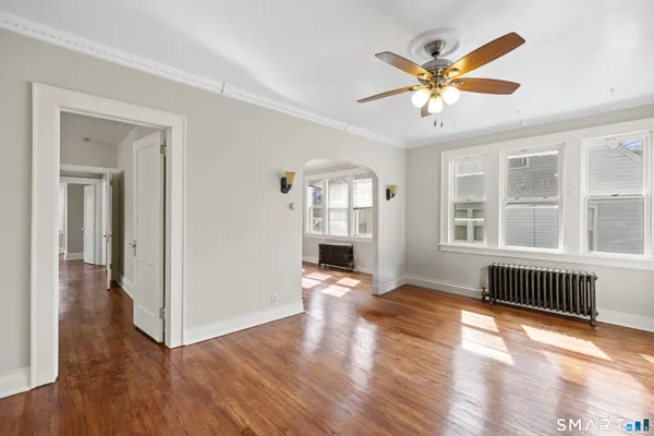 an empty room with wooden floor fan and windows