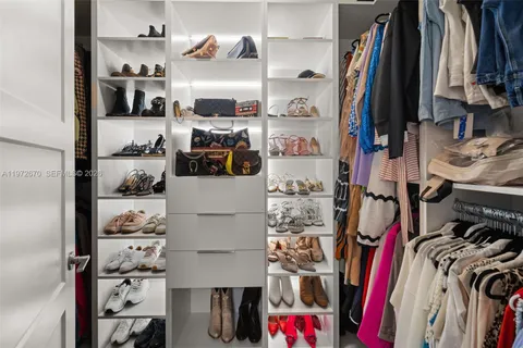 a view of walk in closet with clothes and shoes