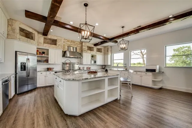 a kitchen with a sink dishwasher a stove a dining table and chairs with wooden floor