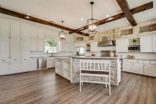 a kitchen with stainless steel appliances granite countertop a table chairs refrigerator and cabinets