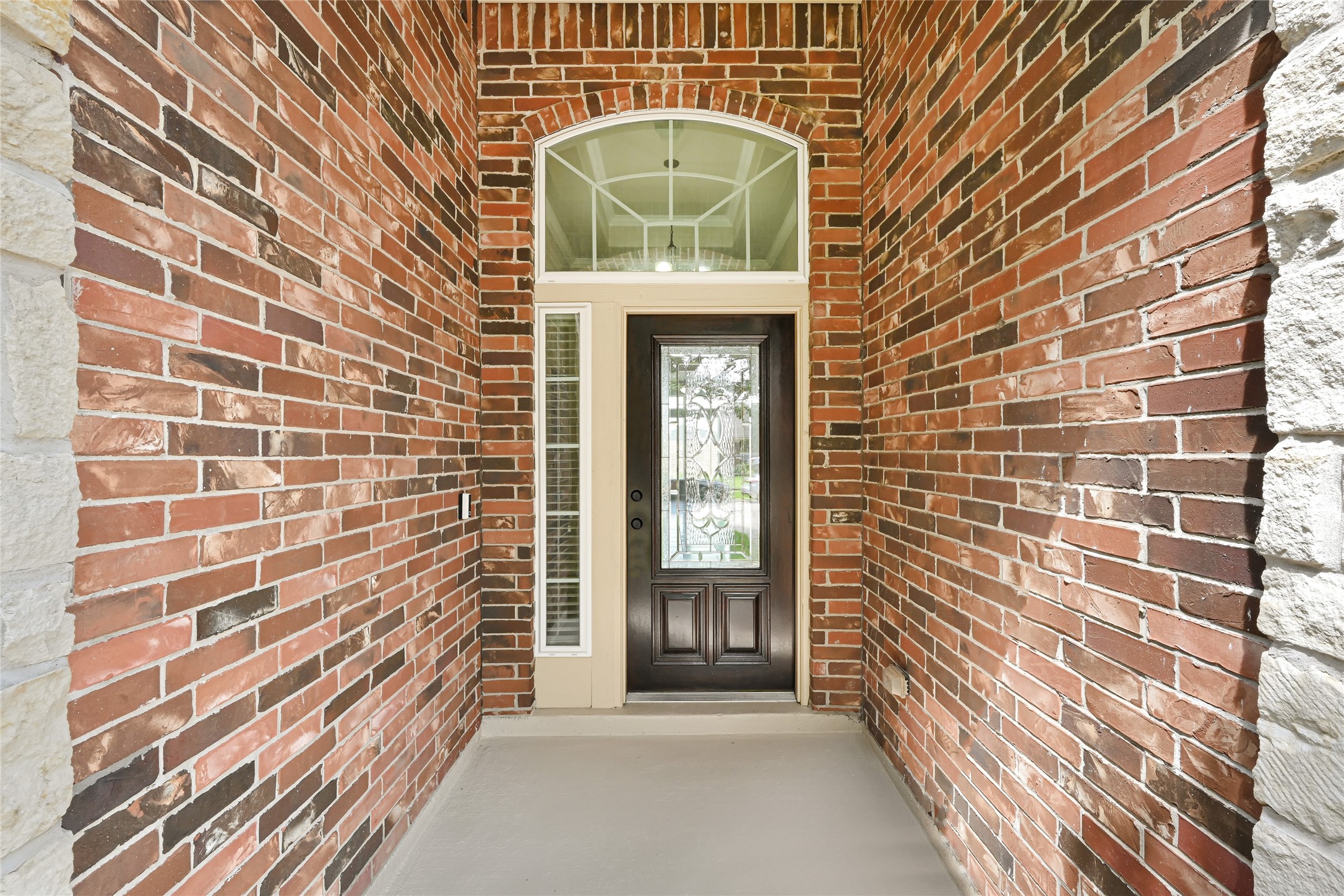 4702 Sedgewood Drive Rosenberg, TX 77471 - Photo 3 of 24 A welcoming brick entryway features a stylish dark wood front door with decorative glass and sidelights, complemented by a transom window above, offering a blend of privacy and natural light.