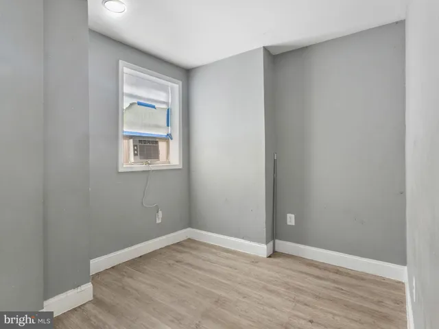 an empty room with wooden floor closet and windows
