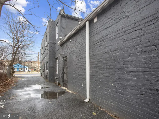 a view of a house with a wooden fence and large trees