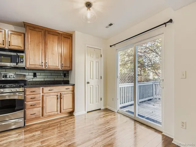 an empty room with wooden floor kitchen view and a window