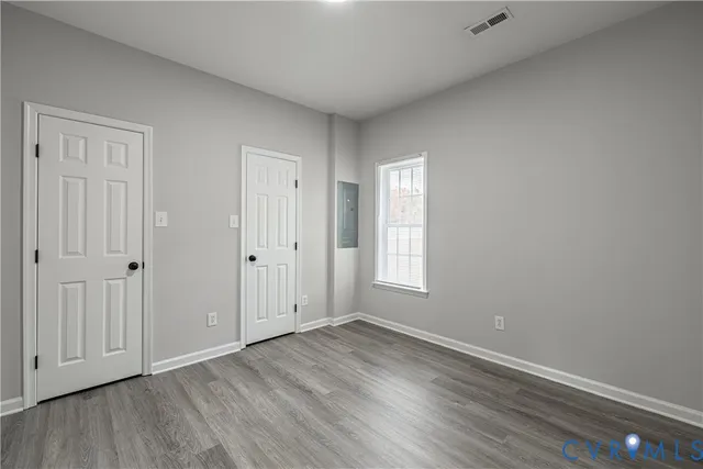 an empty room with wooden floor and windows