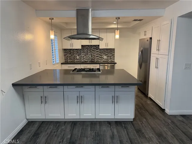 an empty room with wooden floor kitchen view and a window