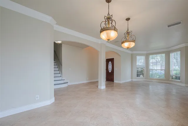 a view of an empty room with window and chandelier