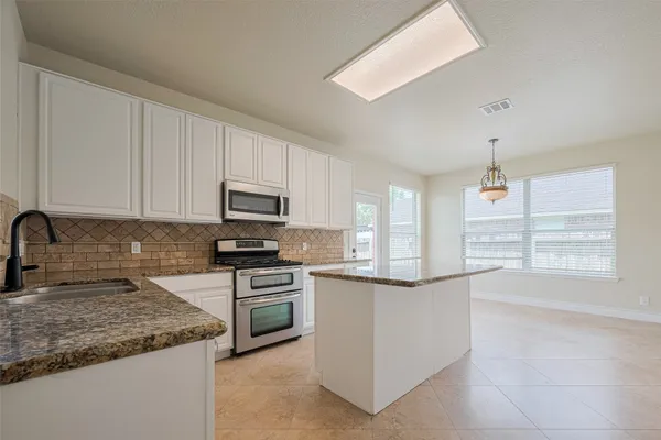 a kitchen with stainless steel appliances granite countertop a stove and a microwave