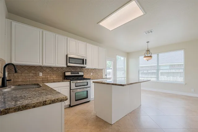 a kitchen with stainless steel appliances granite countertop a stove and a microwave