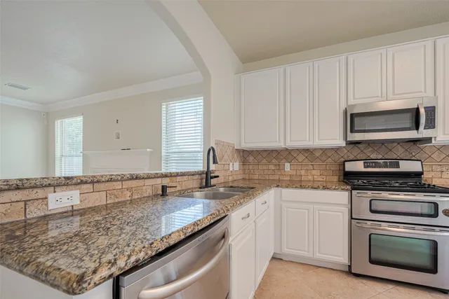 a large kitchen with granite countertop a sink and cabinets