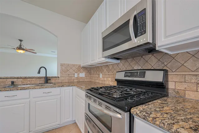 a large kitchen with granite countertop a stove a sink a window and stainless steel appliances