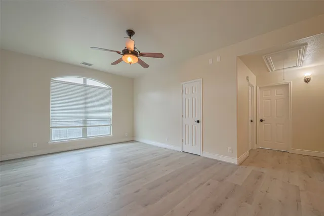 an empty room with wooden floor and windows