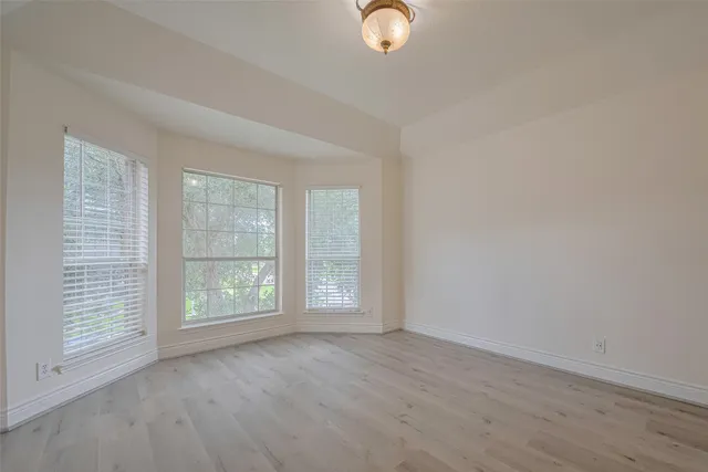 an empty room with wooden floor fan and windows