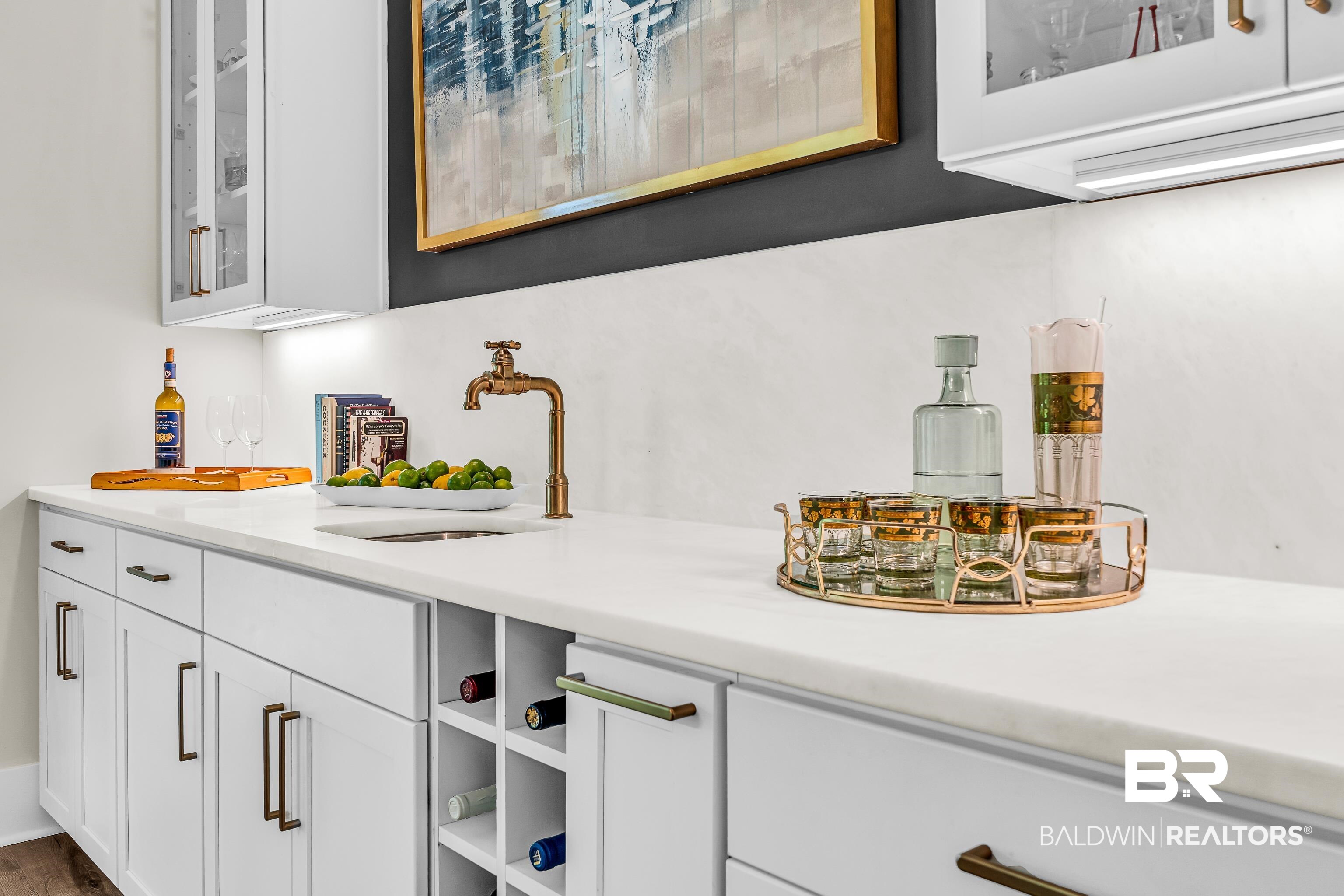 17541 Polo Ridge Boulevard Fairhope, AL 36532 - Photo 2 of 19 Built-in wet bar featuring white cabinetry, a light-toned countertop, and an integrated sink with a brass-finish faucet