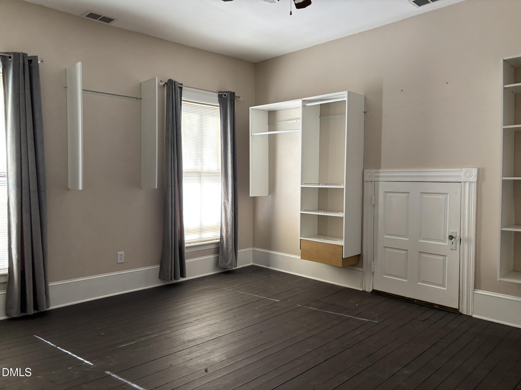 401 North Main Street Louisburg, NC 27549 - Photo 18 of 47 an empty room with wooden floor and windows with curtains