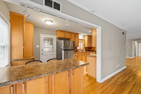 a kitchen with kitchen island granite countertop wooden cabinets and refrigerator