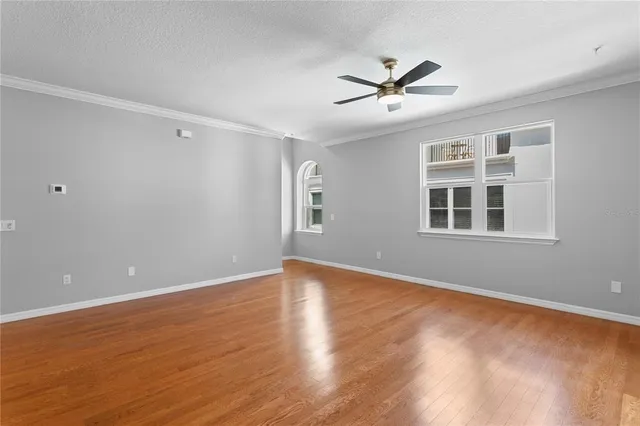 a view of empty room with wooden floor and fan