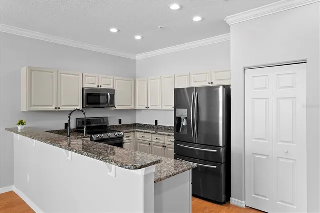 a kitchen with granite countertop a refrigerator stove and microwave