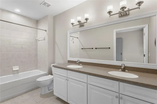 a bathroom with a granite countertop sink a toilet a mirror a vanity a bathtub and shower