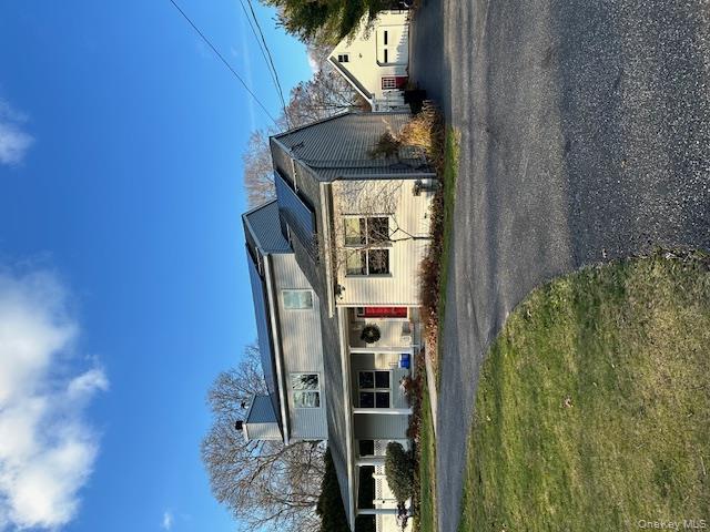 View of front of house featuring an garage , covered porch, front yard, and solar panels