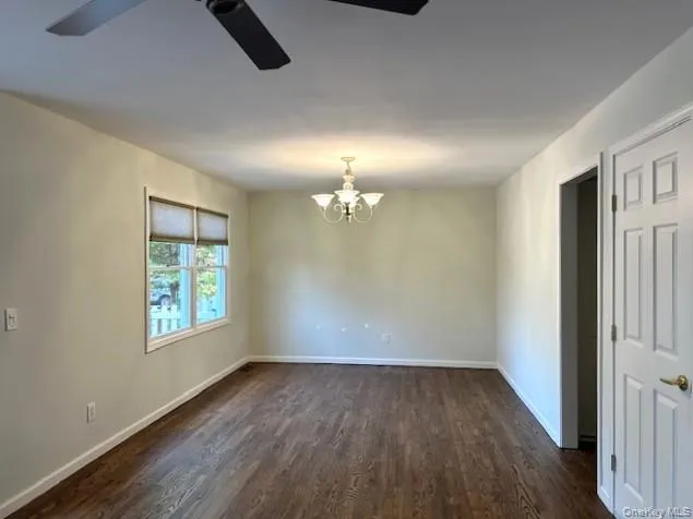 an empty room with wooden floor cabinet and windows