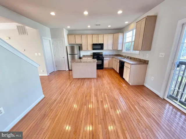 an open kitchen with wooden floor and stainless steel appliances