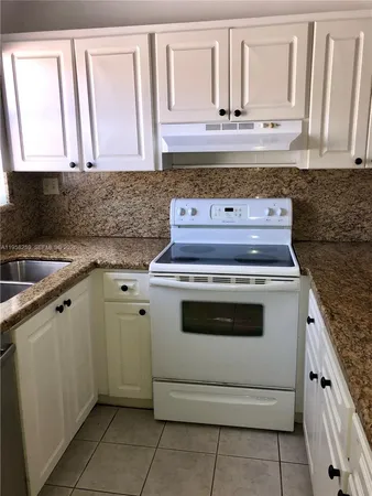 a kitchen with granite countertop white cabinets and white appliances