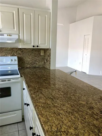 a kitchen with granite countertop white cabinets and white appliances