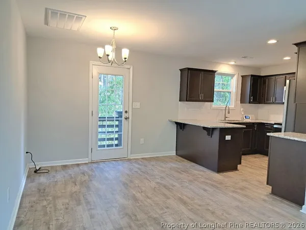 a kitchen with kitchen island granite countertop a stove top oven a sink dishwasher and a refrigerator with wooden floor