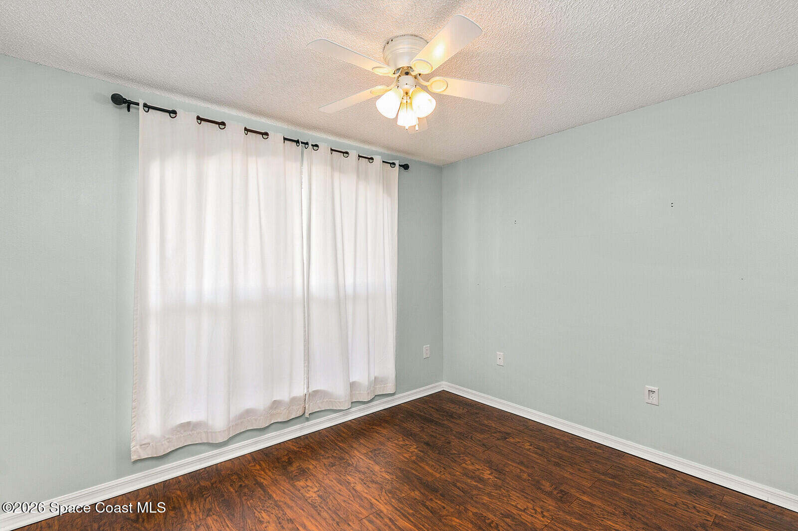 2152 Spring Creek Circle Palm Bay, FL 32905 - Photo 11 of 24 a view of an empty room with a window and wooden floor