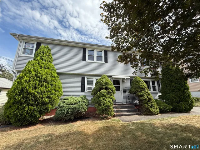 front view of house with potted plants and a yard