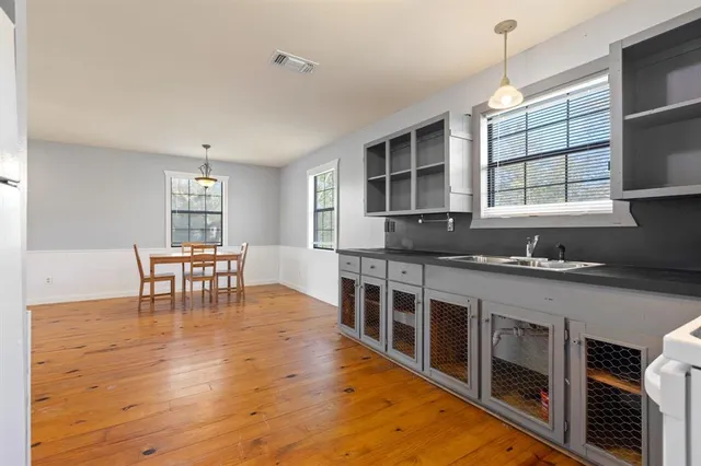 a kitchen with stainless steel appliances granite countertop a stove a sink and a dining table with wooden floor