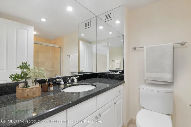 a bathroom with a granite countertop sink a toilet a mirror and shower