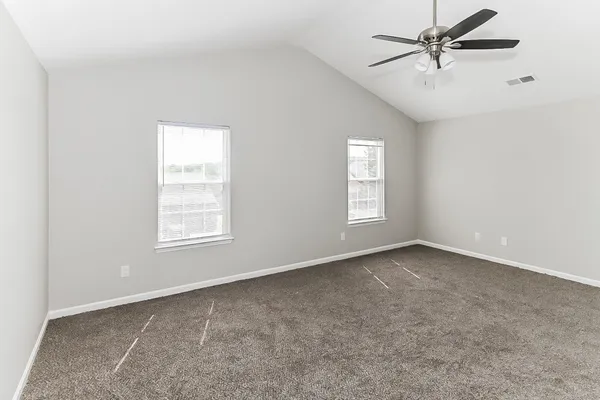 an empty room with windows and fan