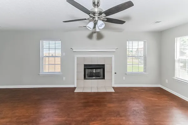 an empty room with windows and fireplace