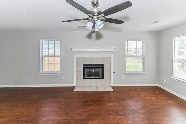 an empty room with windows and fireplace