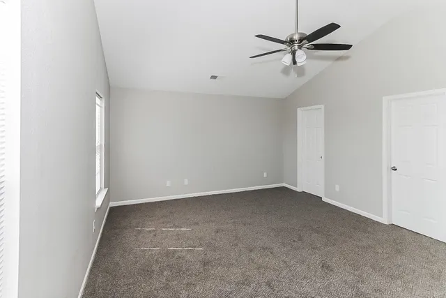 an empty room with a ceiling fan and a window