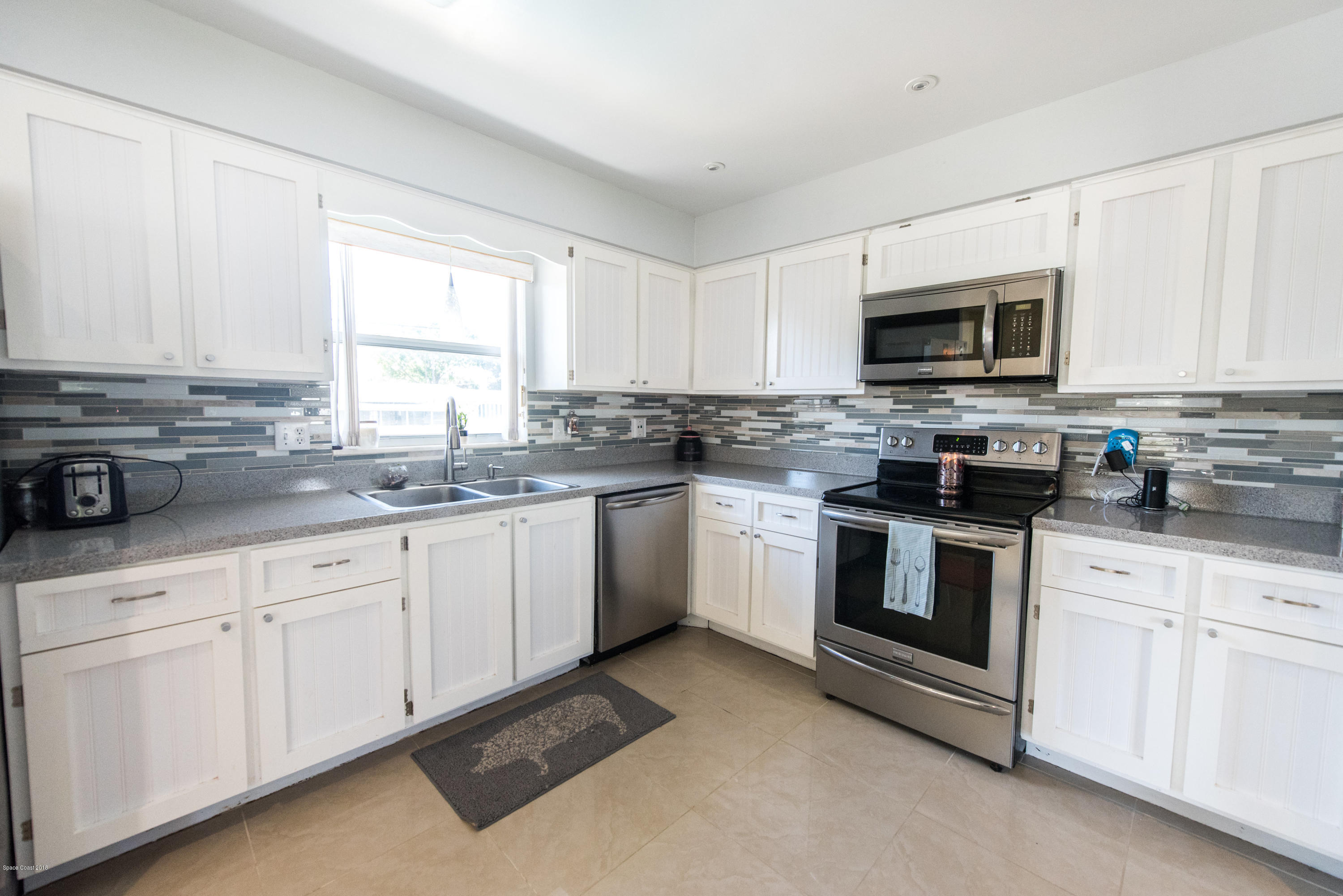 1023 Palmer Road Rockledge, FL 32955 - Photo 2 of 24 a kitchen with white cabinets sink and white appliances