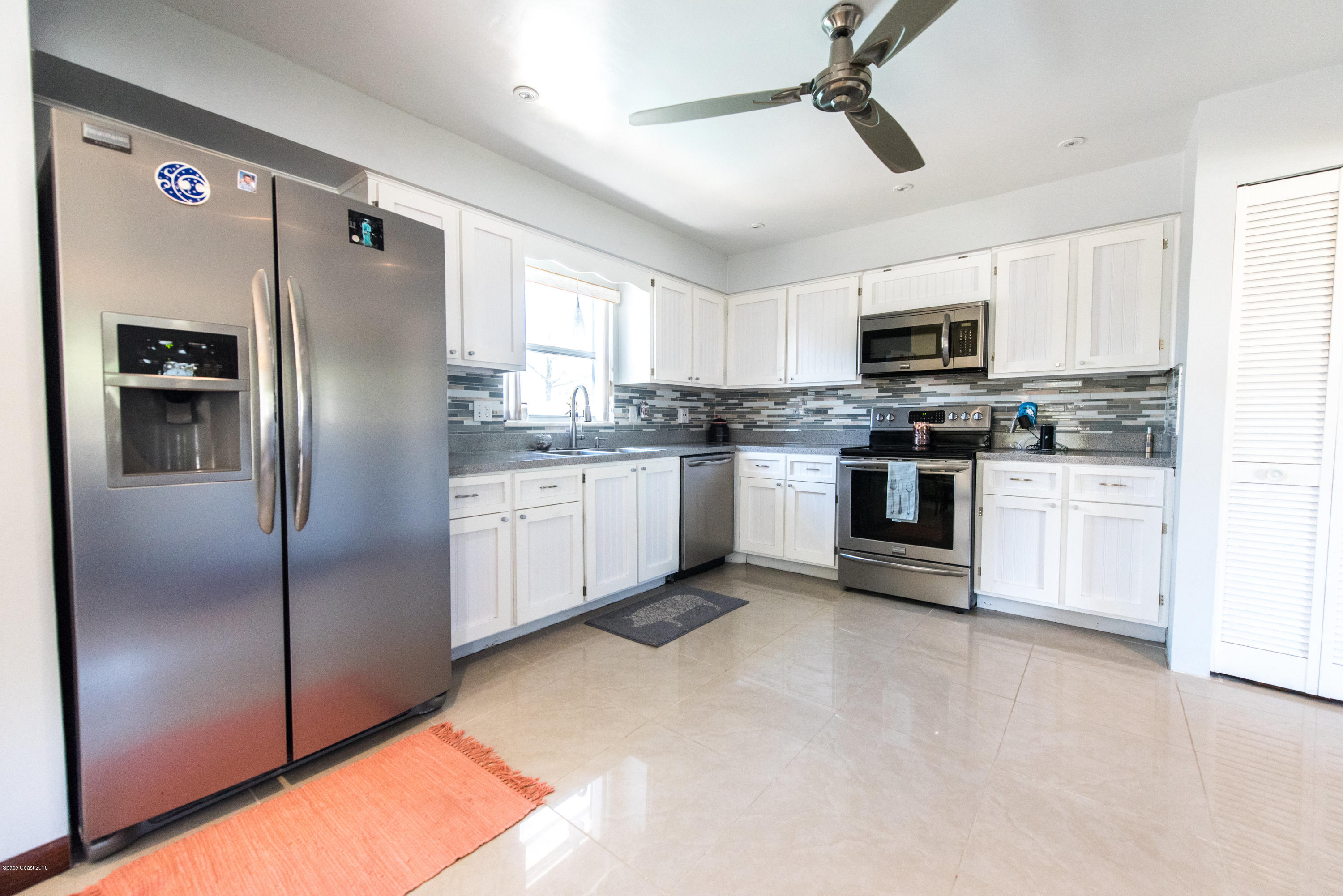 1023 Palmer Road Rockledge, FL 32955 - Photo 3 of 24 a kitchen with stainless steel appliances granite countertop a refrigerator a stove a sink a microwave oven with cabinets and wooden floor