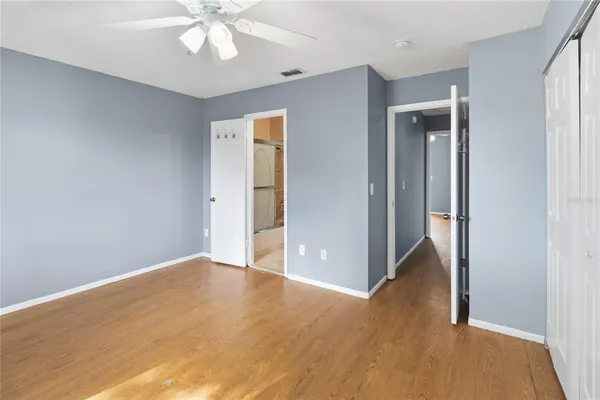 a view of an empty room with wooden floor and a ceiling fan