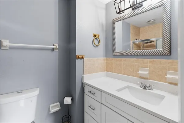 a bathroom with a granite countertop toilet sink and mirror