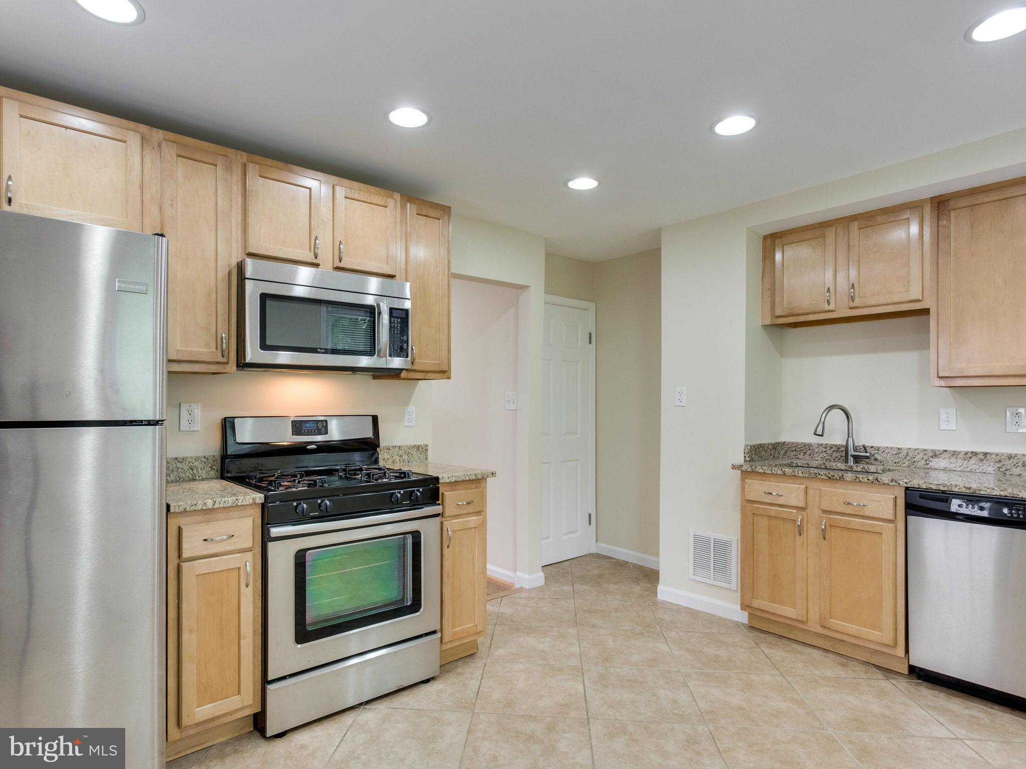 5131 Sheriff Road Northeast Washington, DC 20019 - Photo 8 of 29 a kitchen with stainless steel appliances granite countertop grey cabinets a stove a sink and a refrigerator