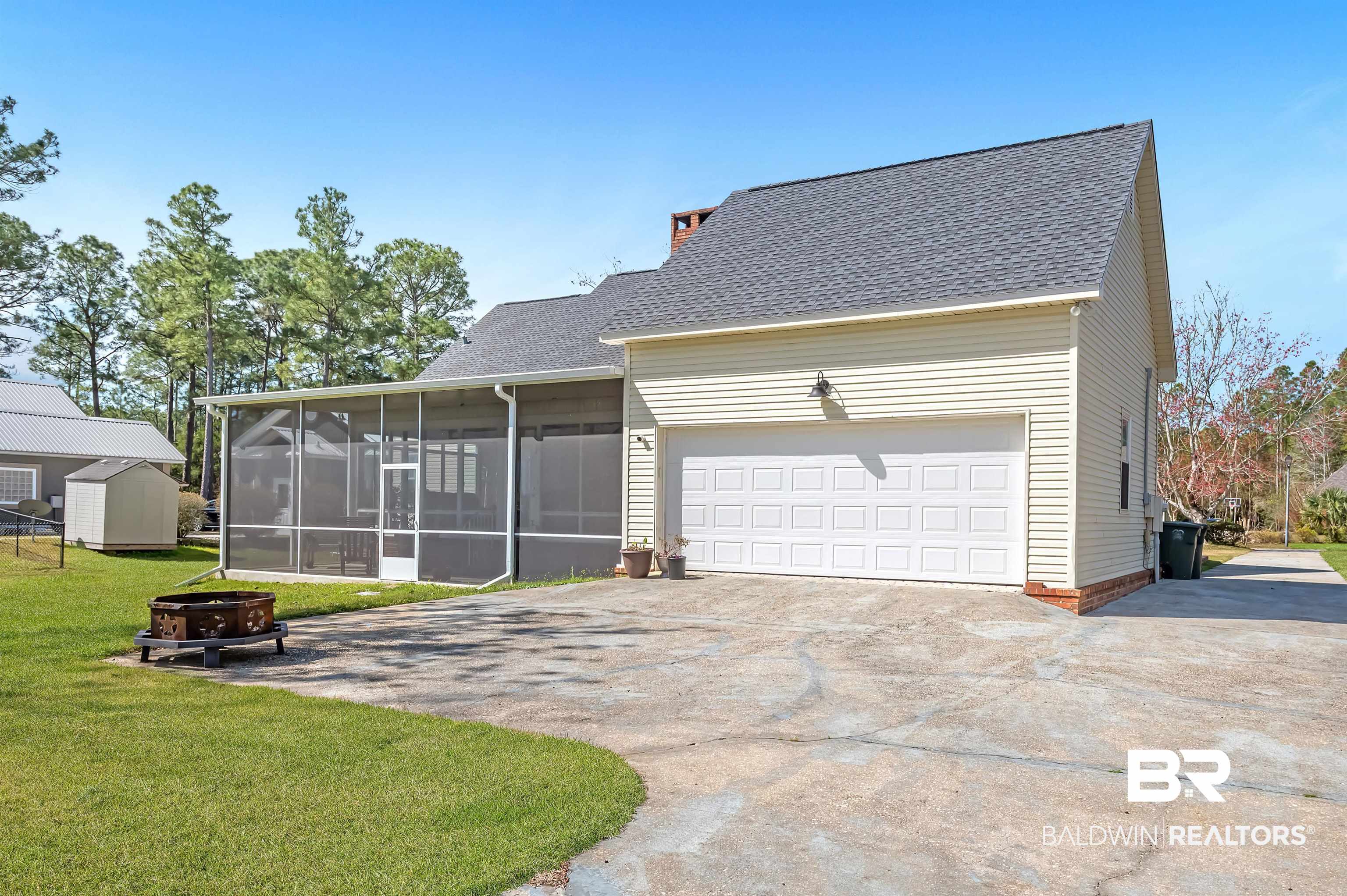 8915 Bay Point Drive Elberta, AL 36530 - Photo 74 of 74 View of front of property featuring driveway, an outdoor fire pit, a front yard, and a sunroom